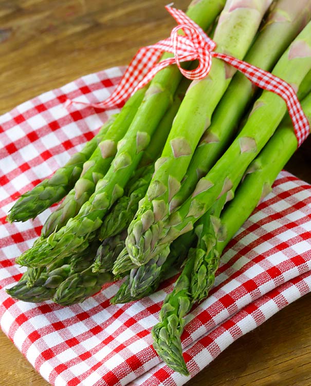 Mary Washington asparagus bundle wrapped with a red gingham ribbon, on top of a red gingham napkin.
